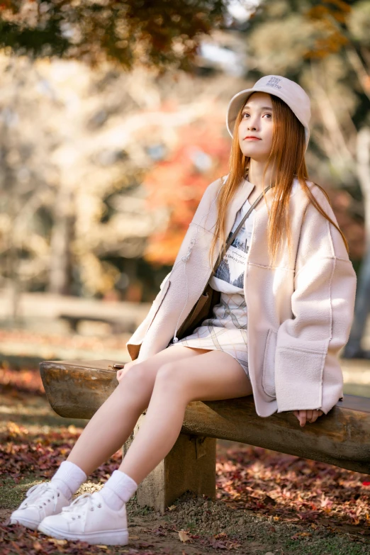 a woman in a hat and coat sits on a park bench