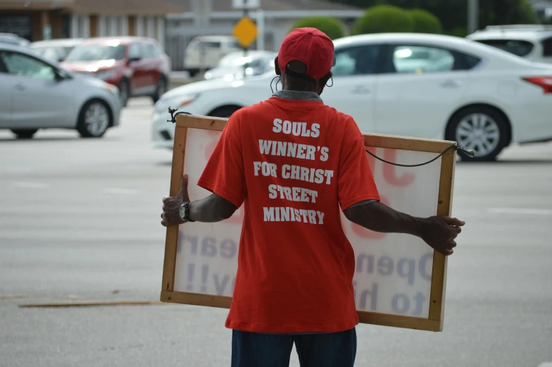 man in red shirt carrying an empty picture frame