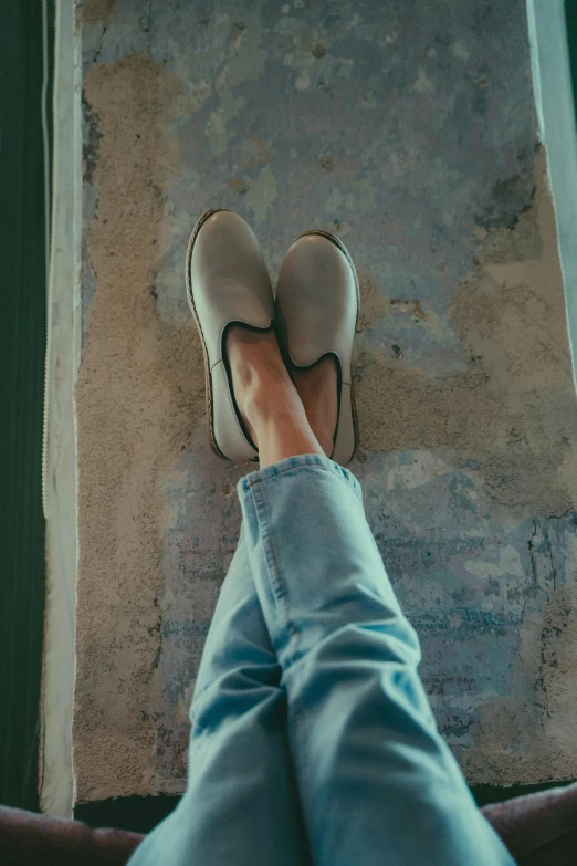 someone's feet are sitting on a stone floor