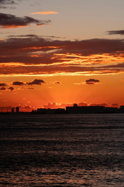 the sun rising above the horizon with buildings in the distance