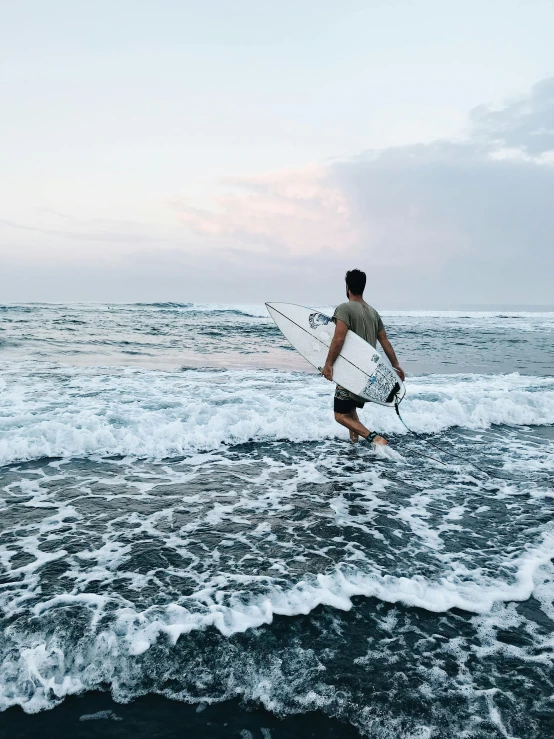 a person carrying a surfboard through the ocean waves