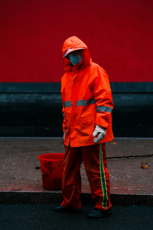 a man in an orange rain jacket and striped pants