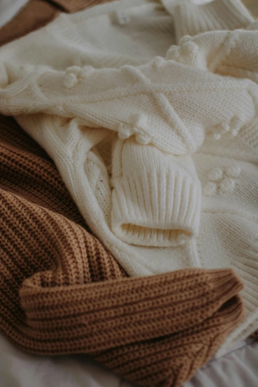 several pieces of sweaters and a coat laid out on the bed