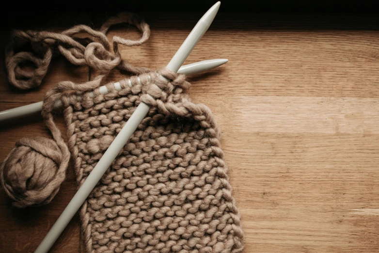 a crocheted wool bag with two knitting needles in it