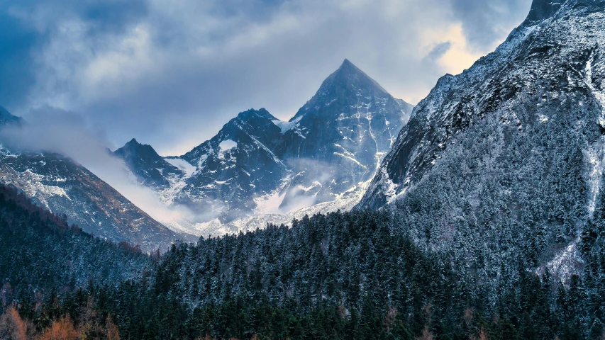 a snowy mountain landscape with lots of clouds