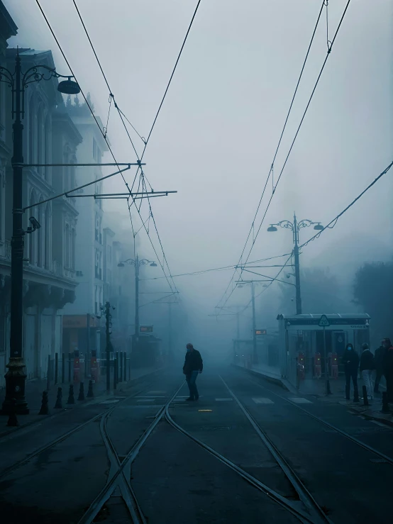 a person walks down the train tracks in the fog