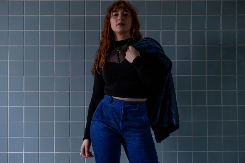 a woman poses in front of a tile wall