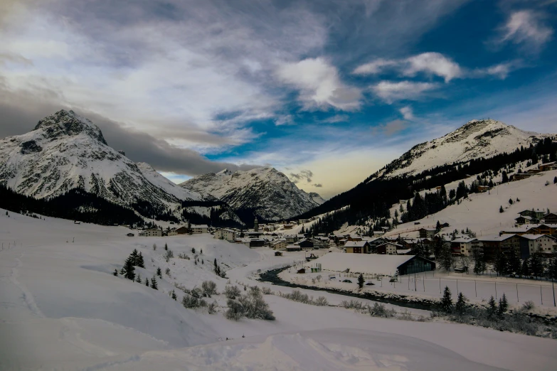 snow covered mountains under a cloudy blue sky