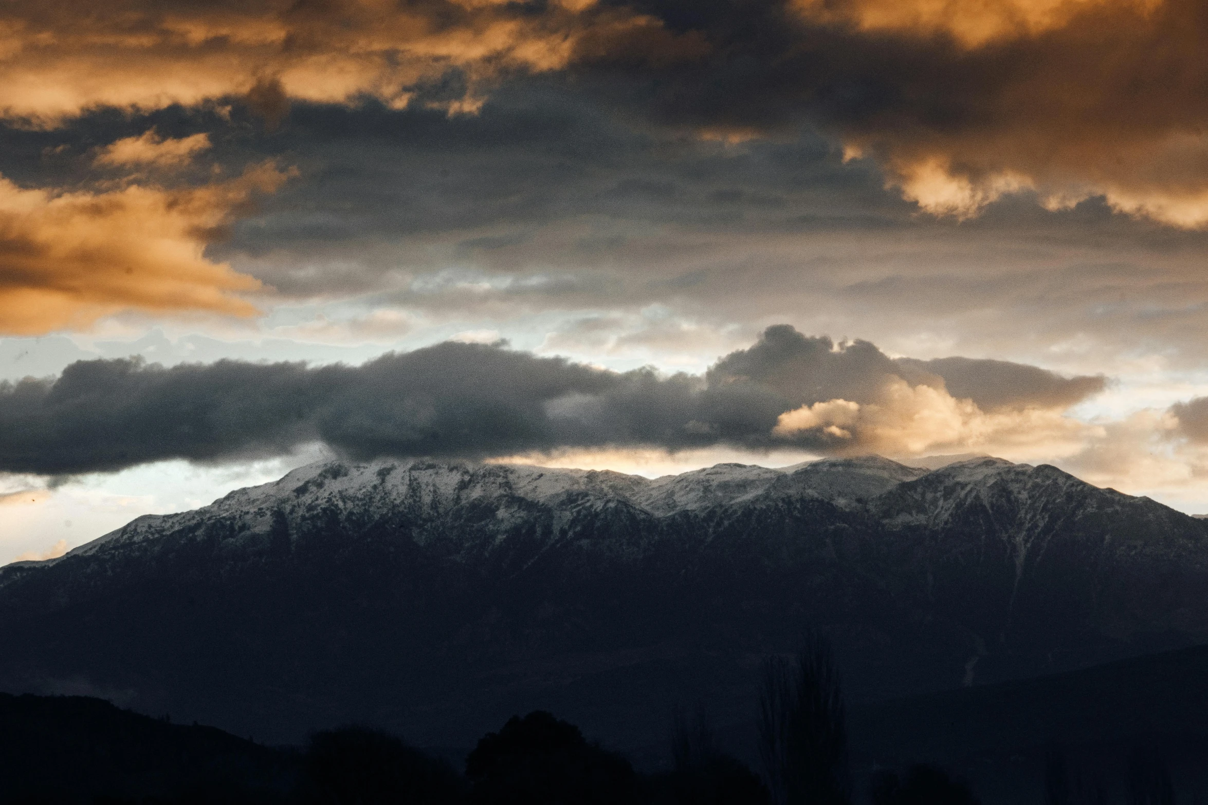 a view of mountains covered in clouds and a cloudy sky