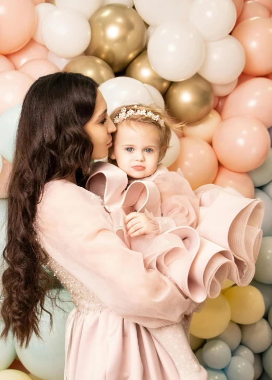 a little girl standing in front of balloons with her mother