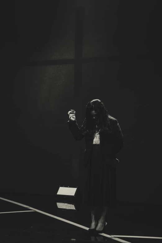 a woman with long hair in black dress standing in a dark room