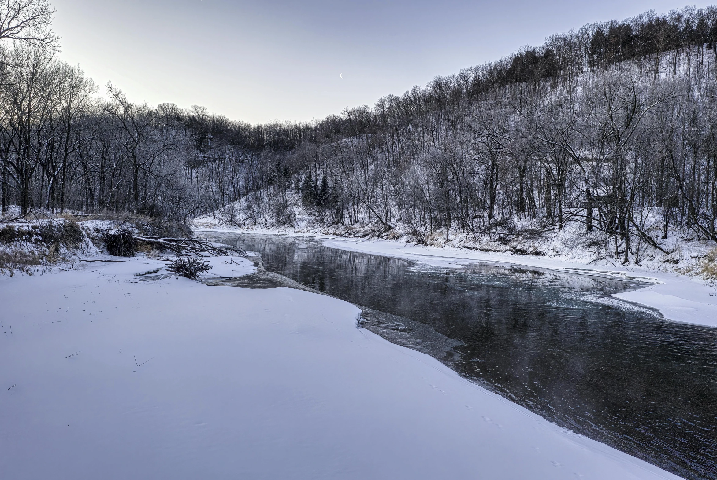 a river surrounded by snow in a forest