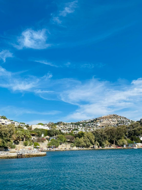 water, a hill and some houses are in the distance