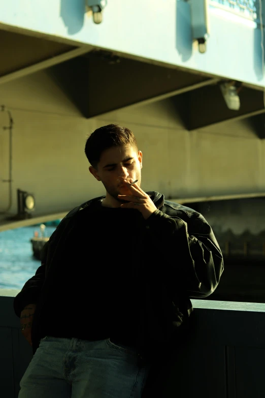 a guy leaning against a wall, smoking a cigarette