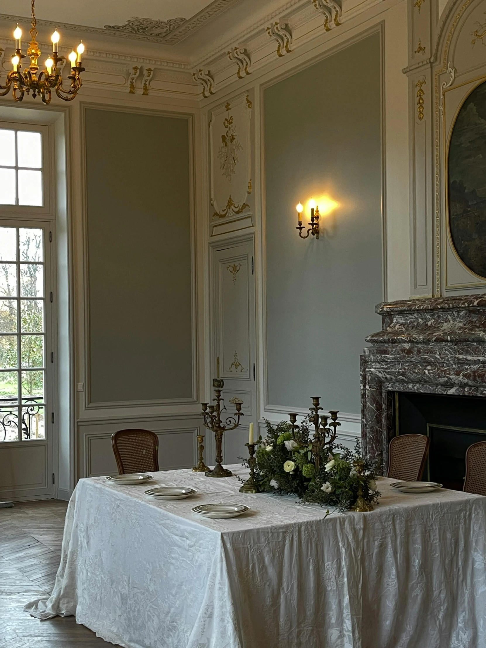 a table in a sitting area with a candle lit chandelier above it