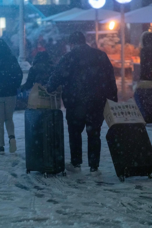 a group of people standing in the snow with luggage