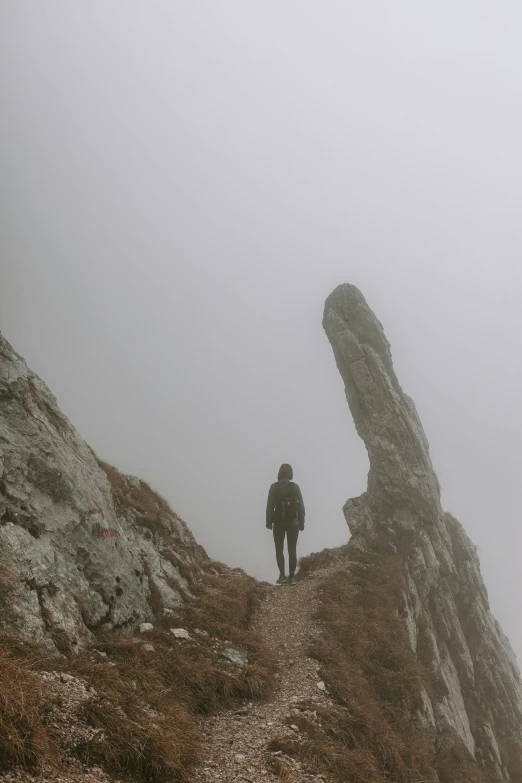 the silhouette of a man standing on top of a large rock