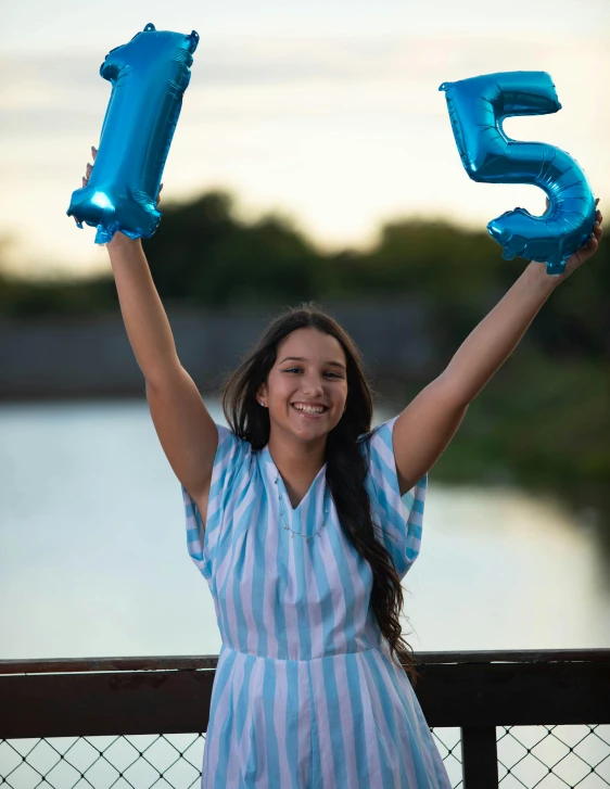 a beautiful young lady holding blue balloons that spell five