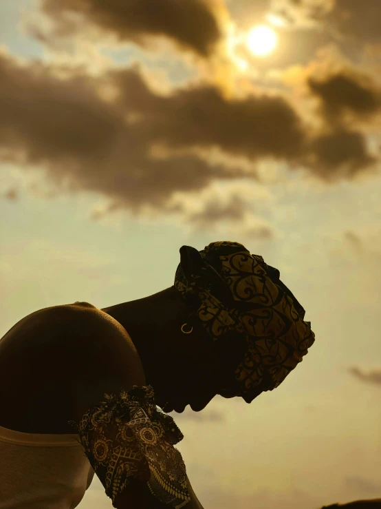 a silhouette of a person wearing headdress against a sky