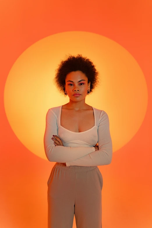 a woman posing in front of a yellow orange background