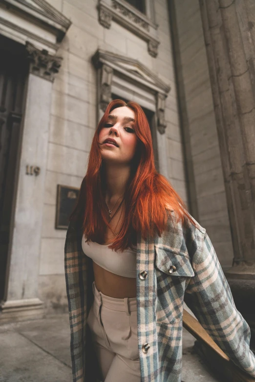woman with red hair in a white crop top outside of building