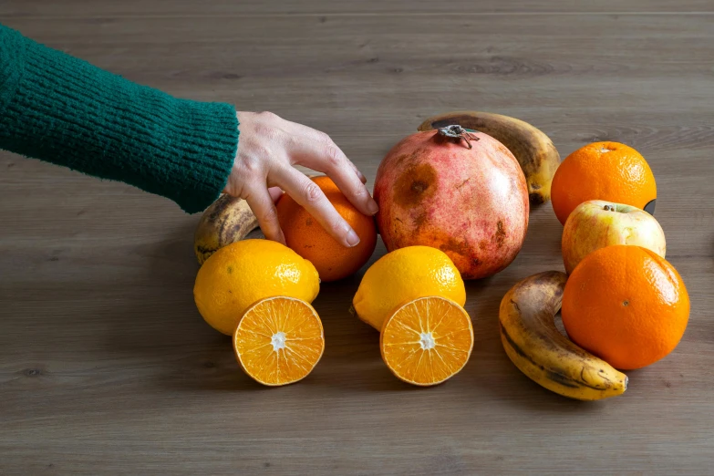 two hands reaching into a fruit arrangement on top of a table