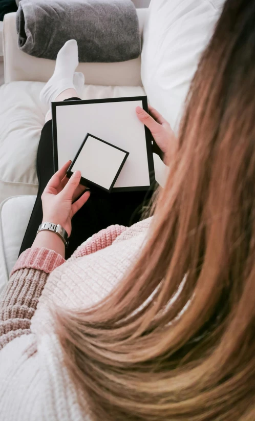 a person sits on a white couch reading a book