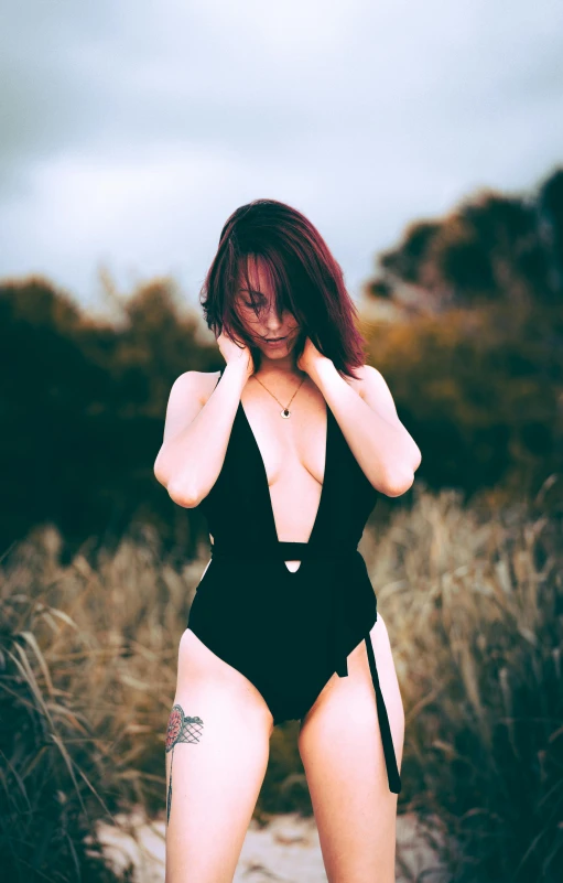 a woman standing in the sand wearing a black bathing suit