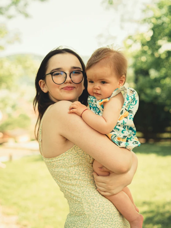 a woman holding a baby wearing glasses