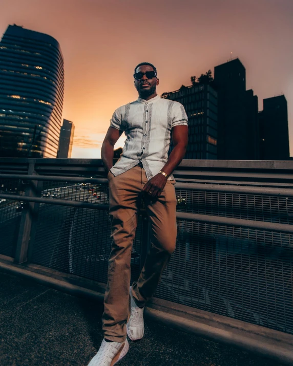 a man standing on the side of a bridge while wearing sunglasses