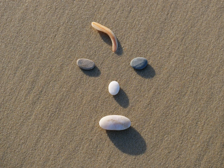 three different stones in the sand with one missing