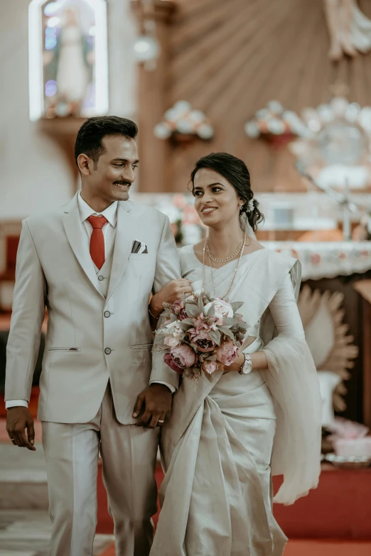 a man and woman in white clothes walk down a aisle