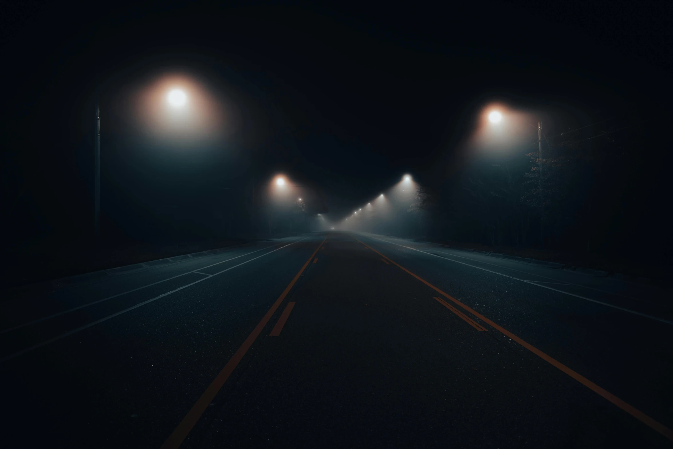 fog rises from a highway as street lights glow down