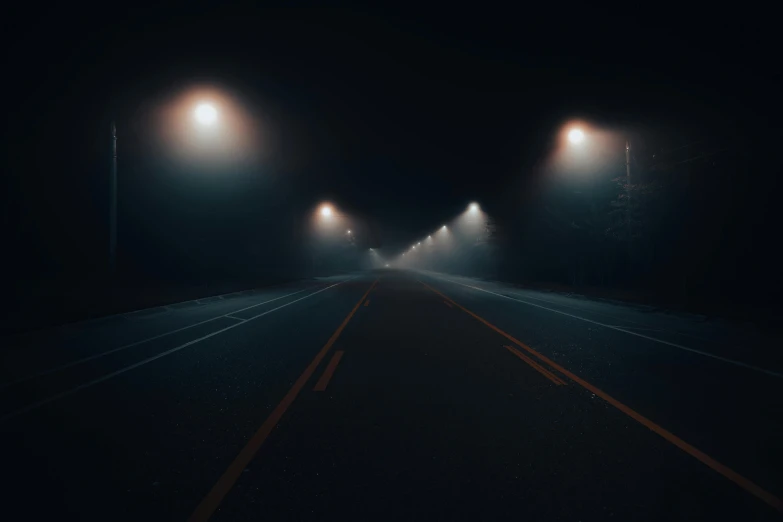 fog rises from a highway as street lights glow down