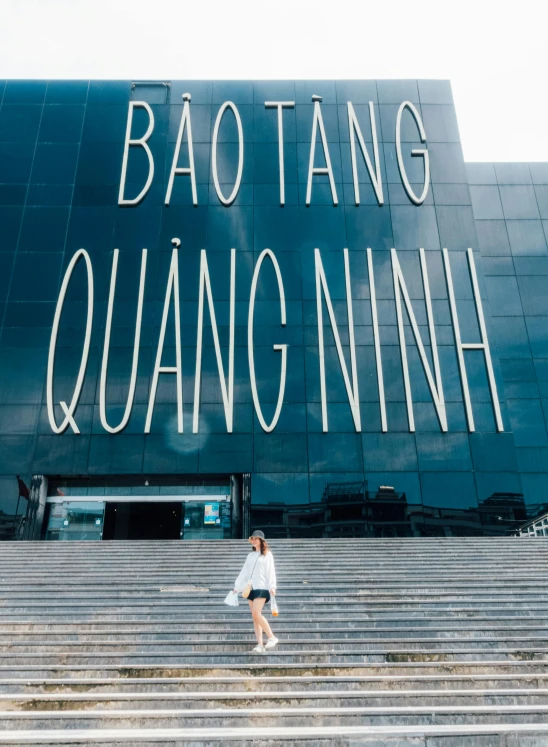 a woman is walking up the steps in front of a large sign