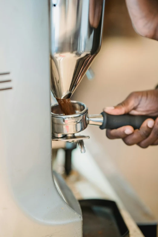 someone pouring coffee into their cup in the coffee maker