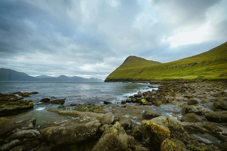 some grass rocks water and hills on the water