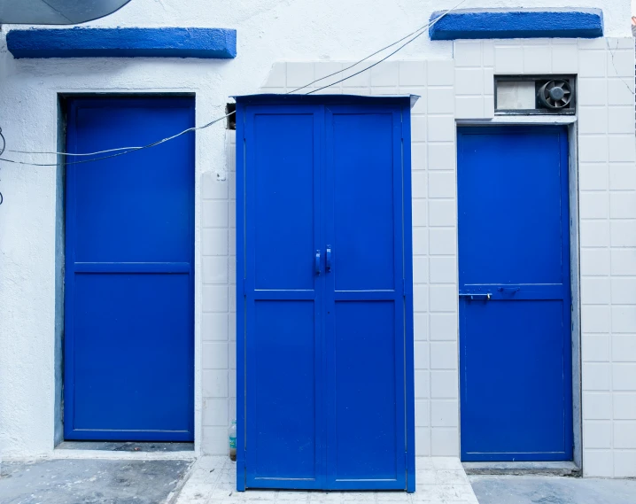 two blue doors that are next to a wall