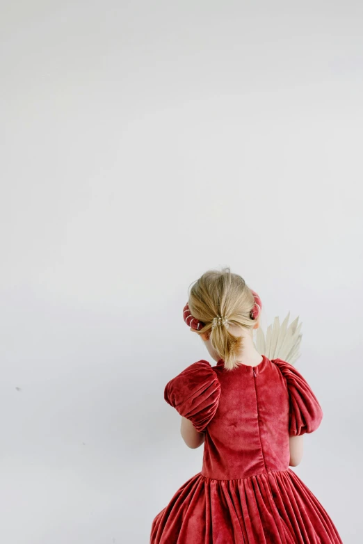 a little girl in a red dress looking at soing