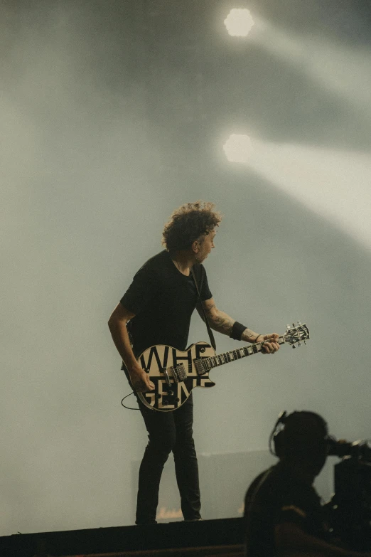 a male with a guitar on top of a stage