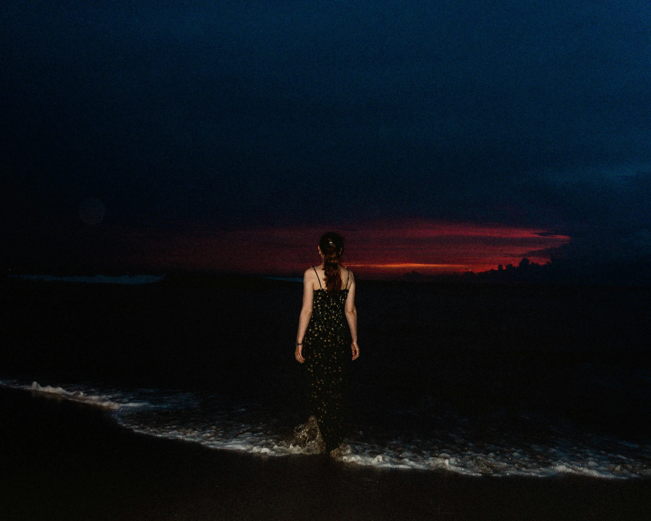 the lady stands in the waves at the beach