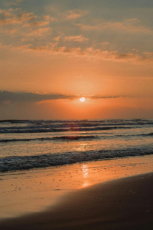 the sun rising over the ocean as seen from the beach