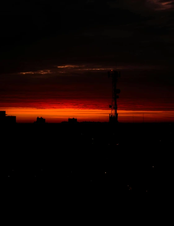 a dark sky is above the city with the sun setting in