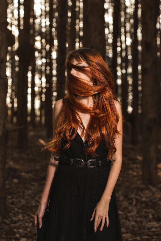 a woman with red hair and a dress is standing in a dark forest