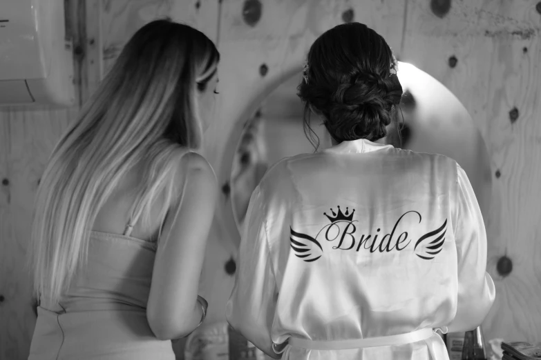 two women in robes are looking into a mirror