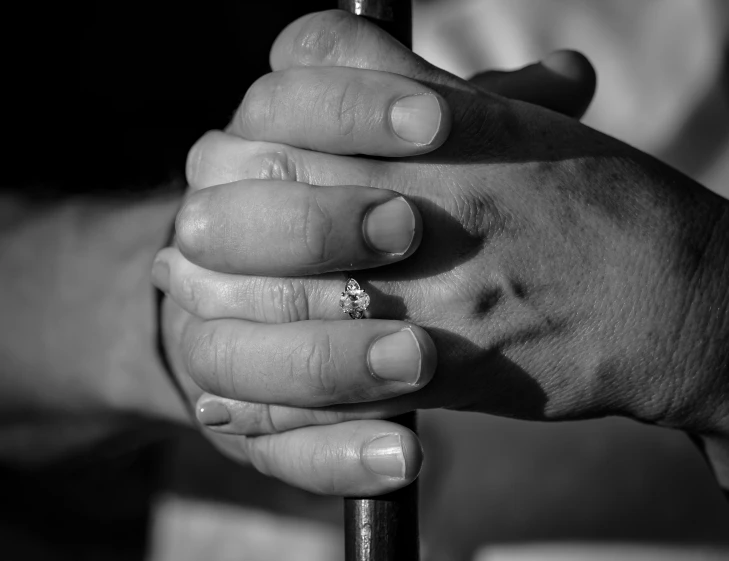 a black and white po of two hands holding a tiny ring