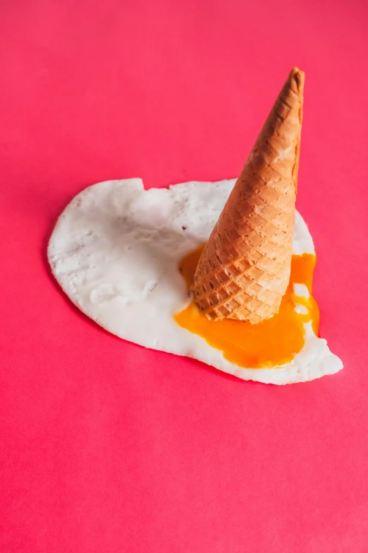 a vanilla ice cream cone sitting on a pink surface