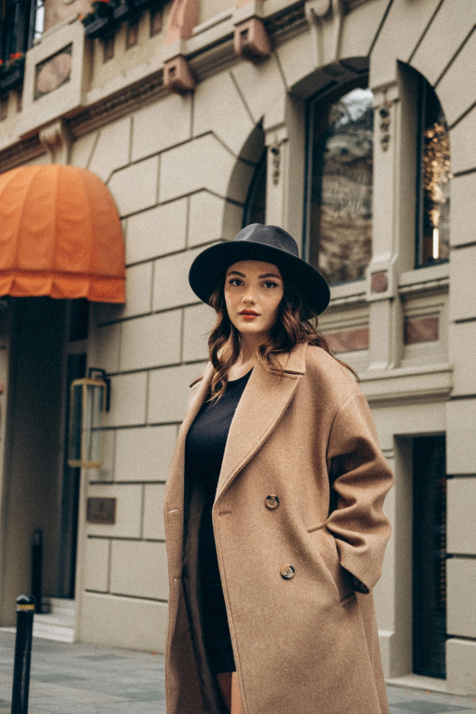 the model is in an elegant hat and trench coat