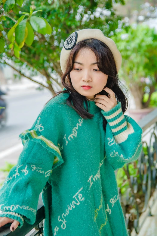 a woman in green is posing near a tree