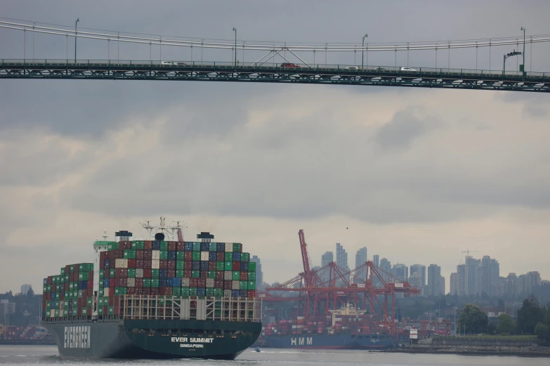 cargo ship leaving port under a suspension bridge